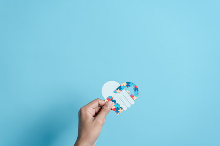 Hand puzzle symbol paper cut out of awareness for autism spectrum disorder family support. Autism World Awareness Dayの写真素材