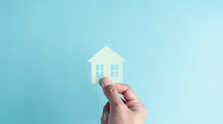Hand holding house paper cut, family home, homeless housing, mortgage crisis and home protection insurance, international day of families, foster home care, family day care, stay home conceptの写真素材