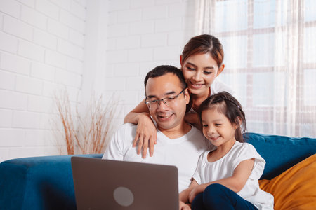 Family parents planing insurance to daughter by laptop computer searching assurance information at home.の写真素材