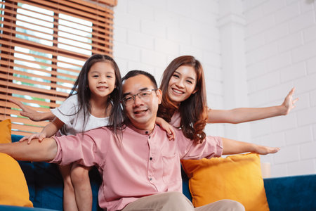 Happy asian family enjoying weekend time relax on couch playing together at home.の写真素材