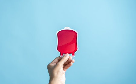 Hands holding blood drop paper cut, blood transfusion, world blood donor day, red cross to give blood.world hemophilia day concept.の写真素材