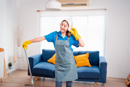 Happy Housework or house keeping service female singing and cleaning dust in house, cleaning agency small business. professional equipment cleaning old home.の写真素材