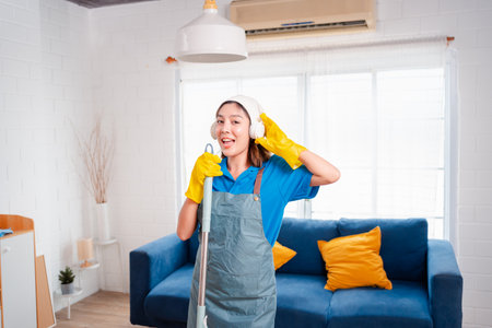Happy Housework or house keeping service female singing and cleaning dust in house, cleaning agency small business. professional equipment cleaning old home.の写真素材