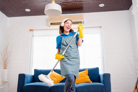 Happy Housework or house keeping service female singing and cleaning dust in house, cleaning agency small business. professional equipment cleaning old home.の写真素材