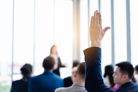 Business person raising hand during seminar. Hand up in conference asking to answer a question in business meeting room and seminar class.