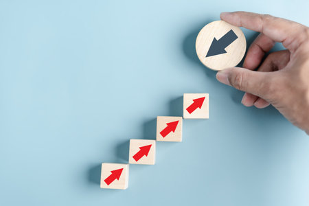 Hand holding wood block with Black arrow and different direction facing opposite direction with red arrow for business disruption and technology transformation and different thinking idea concept.の写真素材