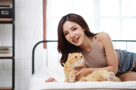 Happy Asian woman owner cute cat playful in a home. Friendship of pet and human people lifestyle.の写真素材
