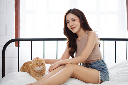 Happy Asian woman owner cute cat playful in a home. Friendship of pet and human people lifestyle.の写真素材