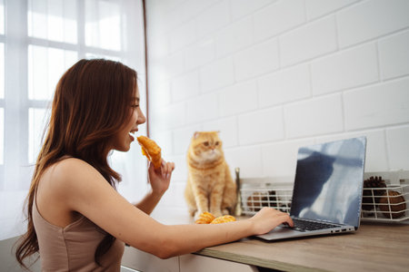 Happy asian young woman working with laptop computer with cute cat in the morning daytime.の写真素材