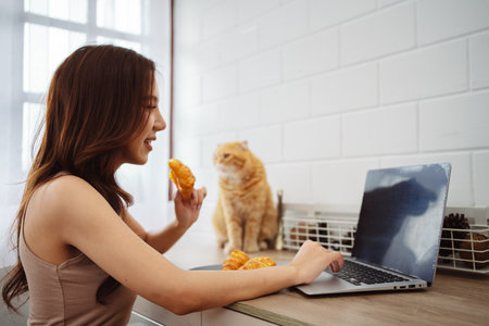 Happy asian young woman working with laptop computer with cute cat in the morning daytime.の写真素材