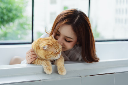 Happy Asian woman owner cute cat playful in a home. Friendship of pet and human people lifestyle.の写真素材