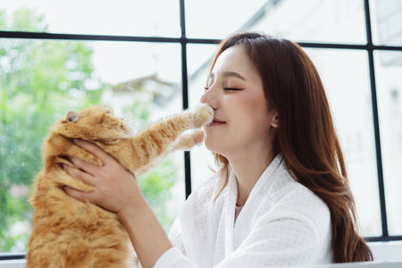 Happy Asian woman owner cute cat playful in a home. Friendship of pet and human people lifestyle.の写真素材