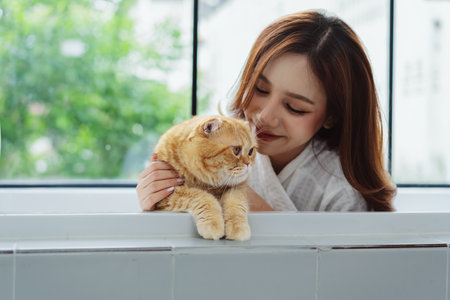 Happy Asian woman owner cute cat playful in a home. Friendship of pet and human people lifestyle.の写真素材