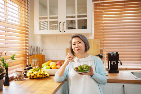 Happy Asian senior woman eating clean food for healthy eating in the kitchen room, Health care concept.の写真素材