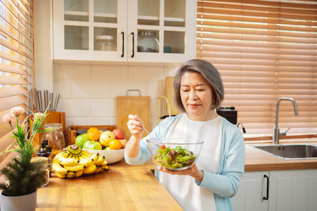 Happy Asian senior woman eating clean food for healthy eating in the kitchen room, Health care concept.の写真素材
