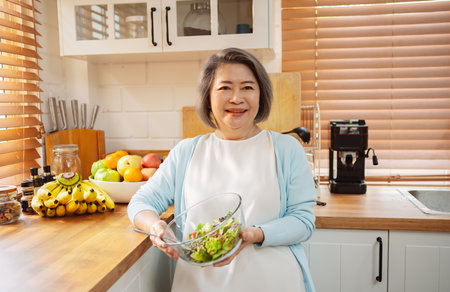 Happy Asian senior woman eating clean food for healthy eating in the kitchen room, Health care concept.の写真素材