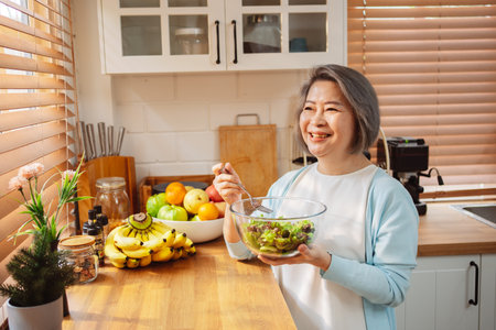 Happy Asian senior woman eating clean food for healthy eating in the kitchen room, Health care concept.の写真素材