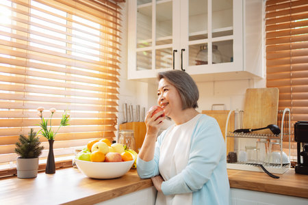 Happy Asian senior woman eating clean food for healthy eating in the kitchen room, Health care concept.の写真素材