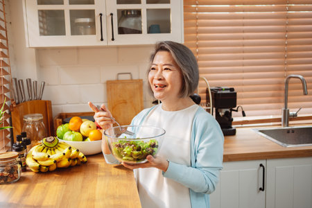 Happy Asian senior woman eating clean food for healthy eating in the kitchen room, Health care concept.の写真素材