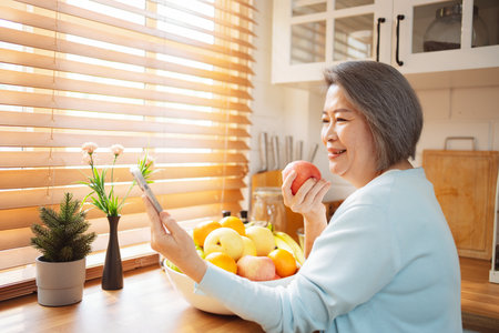 Happy Asian senior woman eating clean food for healthy eating in the kitchen room, Health care concept.の写真素材