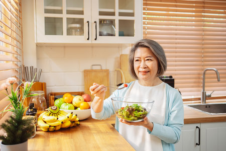 Happy Asian senior woman eating clean food for healthy eating in the kitchen room, Health care concept.の写真素材