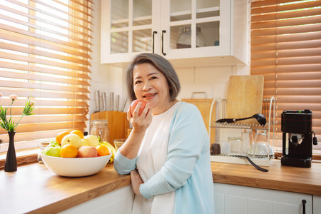 Happy Asian senior woman eating clean food for healthy eating in the kitchen room, Health care concept.の写真素材