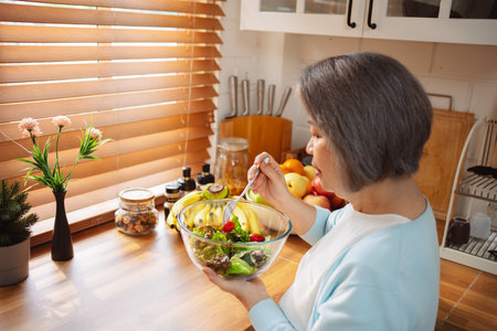 Happy Asian senior woman eating clean food for healthy eating in the kitchen room, Health care concept.の写真素材