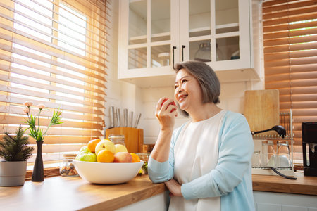 Happy Asian senior woman eating clean food for healthy eating in the kitchen room, Health care concept.の写真素材