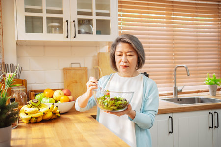 Happy Asian senior woman eating clean food for healthy eating in the kitchen room, Health care concept.の写真素材