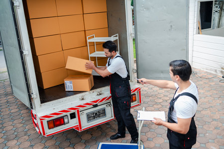 Unloading boxes and furniture from a pickup truck to a new house with service cargo two men movers worker in uniform lifting boxes. concept of Home moving and delivery.の写真素材