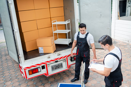 Unloading boxes and furniture from a pickup truck to a new house with service cargo two men movers worker in uniform lifting boxes. concept of Home moving and delivery.の写真素材