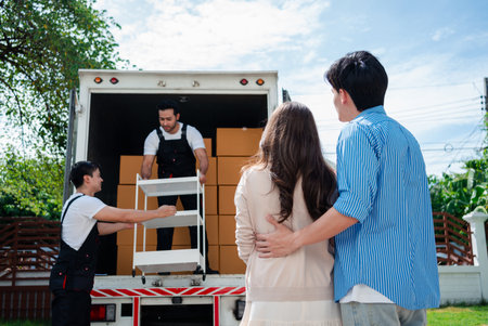 Asian Couple check while unloading boxes and furniture from a pickup truck to a new house with service cargo two men movers worker in uniform lifting boxes. concept of Home moving and delivery.の写真素材