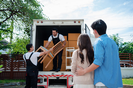 Asian Couple check while unloading boxes and furniture from a pickup truck to a new house with service cargo two men movers worker in uniform lifting boxes. concept of Home moving and delivery.の写真素材