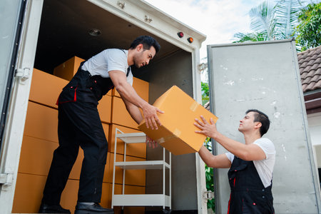Unloading boxes and furniture from a pickup truck to a new house with service cargo two men movers worker in uniform lifting boxes. concept of Home moving and delivery.の写真素材