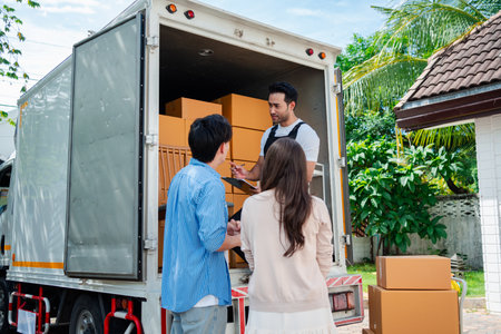 Asian Couple check while unloading boxes and furniture from a pickup truck to a new house with service cargo two men movers worker in uniform lifting boxes. concept of Home moving and delivery.の写真素材