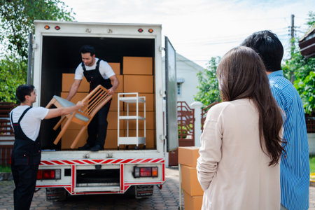 Asian Couple check while unloading boxes and furniture from a pickup truck to a new house with service cargo two men movers worker in uniform lifting boxes. concept of Home moving and delivery.の写真素材