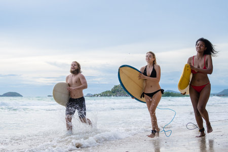 Group Friendship playing surfboard on the beach in weekend activity, Sport extreme healthy lifestyle concept.の写真素材