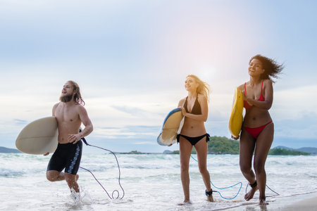Group Friendship playing surfboard on the beach in weekend activity, Sport extreme healthy lifestyle concept.の写真素材