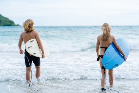 Couple playing surfboard on the beach in weekend activity, Sport extreme healthy lifestyle concept.の写真素材
