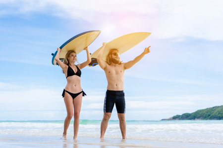 Couple playing surfboard on the beach in weekend activity, Sport extreme healthy lifestyle concept.の写真素材