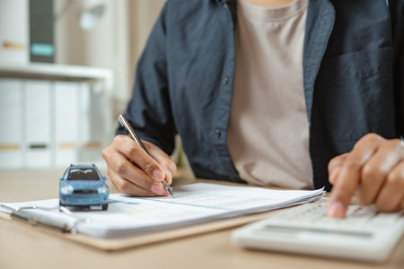 Man signing car insurance on paperwork assurance. Buying or selling new vehicle. Ownership for new car or rent concept.の写真素材