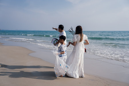 Happy Family of volunteers worker cleaning plastic bottle on the beach with trash bags.