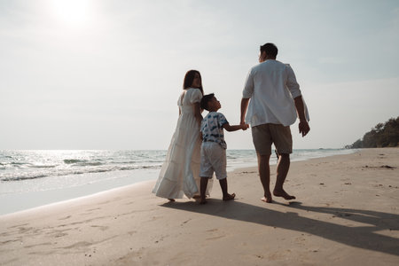 Happy asian family enjoy together on the beach in holiday vacation. family holding hands enjoying the sunset on the sea beach. Happy family travel, trip  family holidays weekend.の写真素材