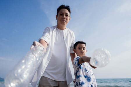 Happy Family of volunteers worker cleaning plastic bottle on the beach with trash bags.の写真素材