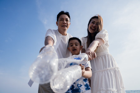 Happy Family of volunteers worker cleaning plastic bottle on the beach with trash bags.の写真素材