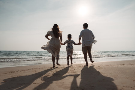 Happy asian family enjoy together on the beach in holiday vacation. family holding hands enjoying the sunset on the sea beach. Happy family travel, trip  family holidays weekend.の写真素材