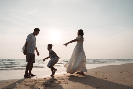 Happy asian family enjoy together on the beach in holiday vacation. Silhouette of the family holding hands enjoying the sunset on the sea beach. Happy family travel, trip  family holidays weekend.の写真素材