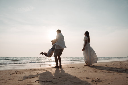 Happy asian family enjoy together on the beach in holiday vacation. Silhouette of the family holding hands enjoying the sunset on the sea beach. Happy family travel, trip  family holidays weekend.の写真素材