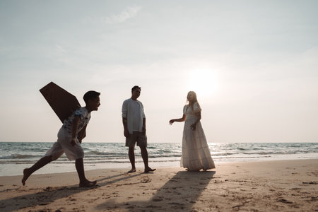 Happy asian family enjoy together on the beach in holiday vacation. Silhouette of the family holding hands enjoying the sunset on the sea beach. Happy family travel, trip  family holidays weekend.の写真素材