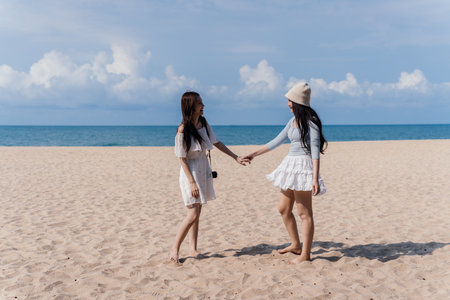 Woman Friendship Beach Walking Coastline Togetherness Female Vacation Outdoors Nature, Joyful Young Women Enjoying a Carefree Summer Walk Along the Seaside with Laughter and Bonding Momentsの写真素材